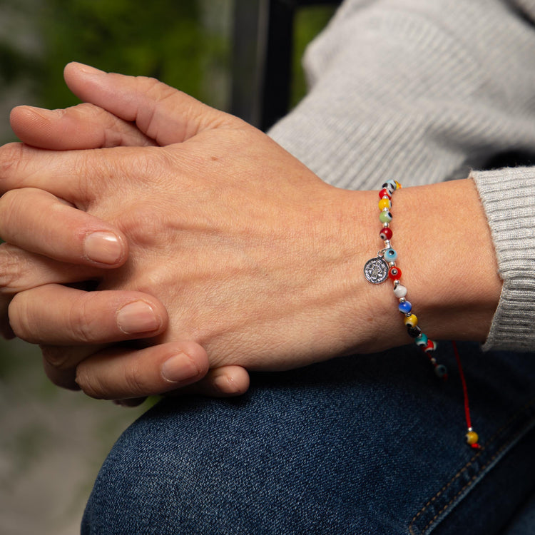 Pulsera de hilo con dije de San Benito de plata y ojos turcos